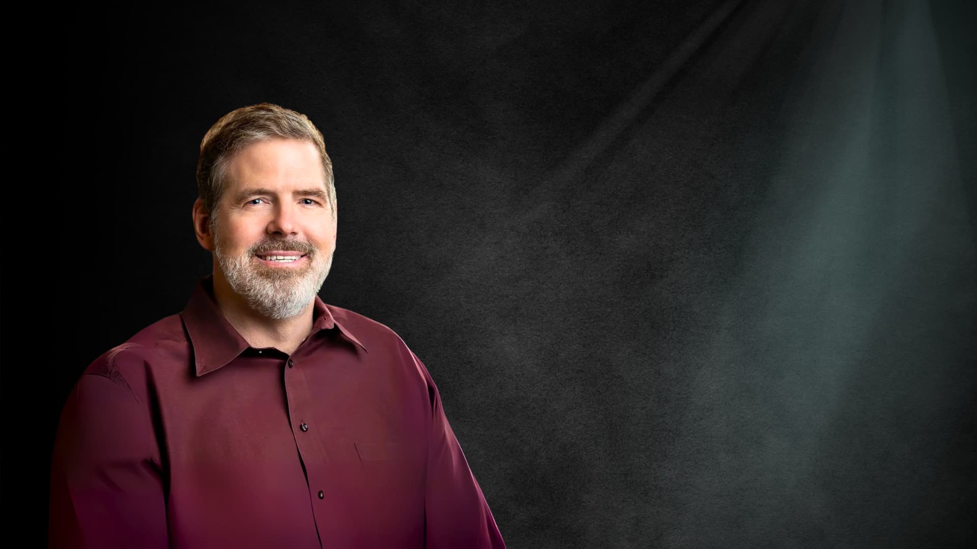 Studio portrait of Scott Allen Frost, keynote speaker and author, smiling in a maroon shirt.